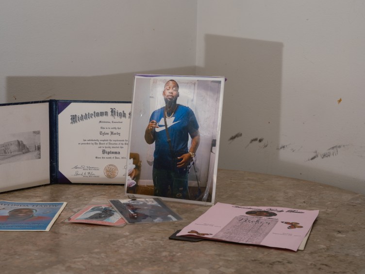 A photo of a man posing for a photo sits next to a diploma on a table.