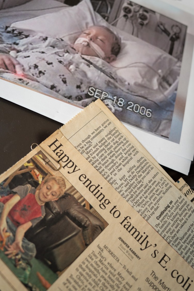   Foto eines Jungen in einem Krankenhausbett neben einem Zeitungsausschnitt mit der Überschrift „Happy End für E. coli in der Familie“.