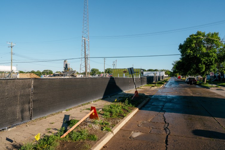 A photograph from the same vantage point shows a fenced-in lot with construction equipment and a cracked sidewalk.