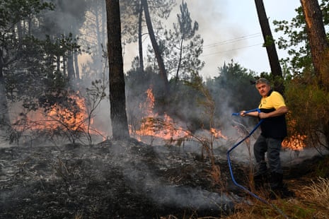 Un habitant utilise un tuyau pour éteindre les flammes qui brûlent en face de sa maison près de Marcheprime, près de Bordeaux, en France.
