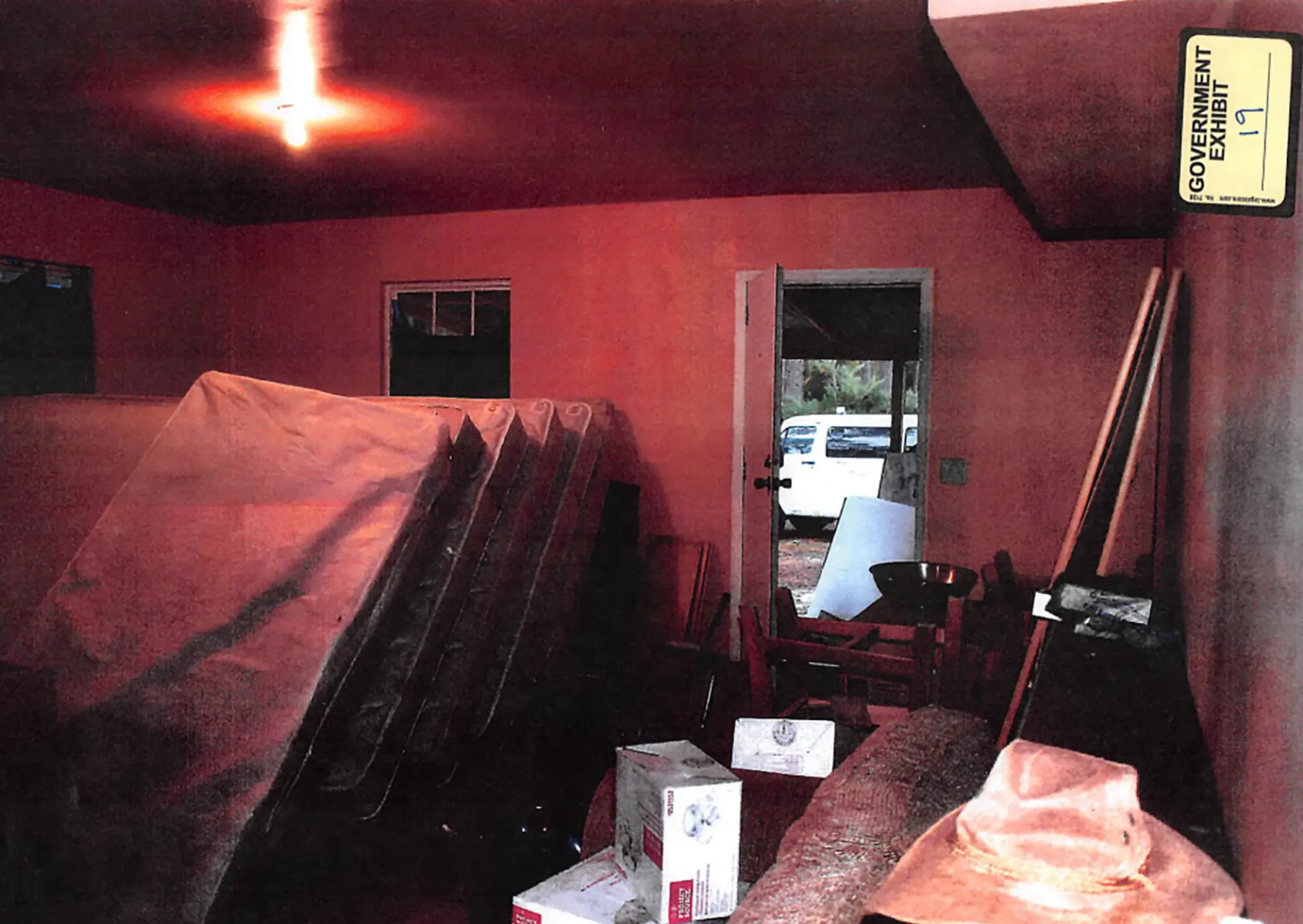 Une pièce rouge faiblement éclairée remplie de matelas empilés verticalement.