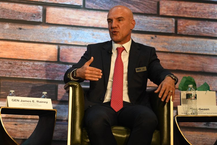 A man in a suit speaks on a stage.