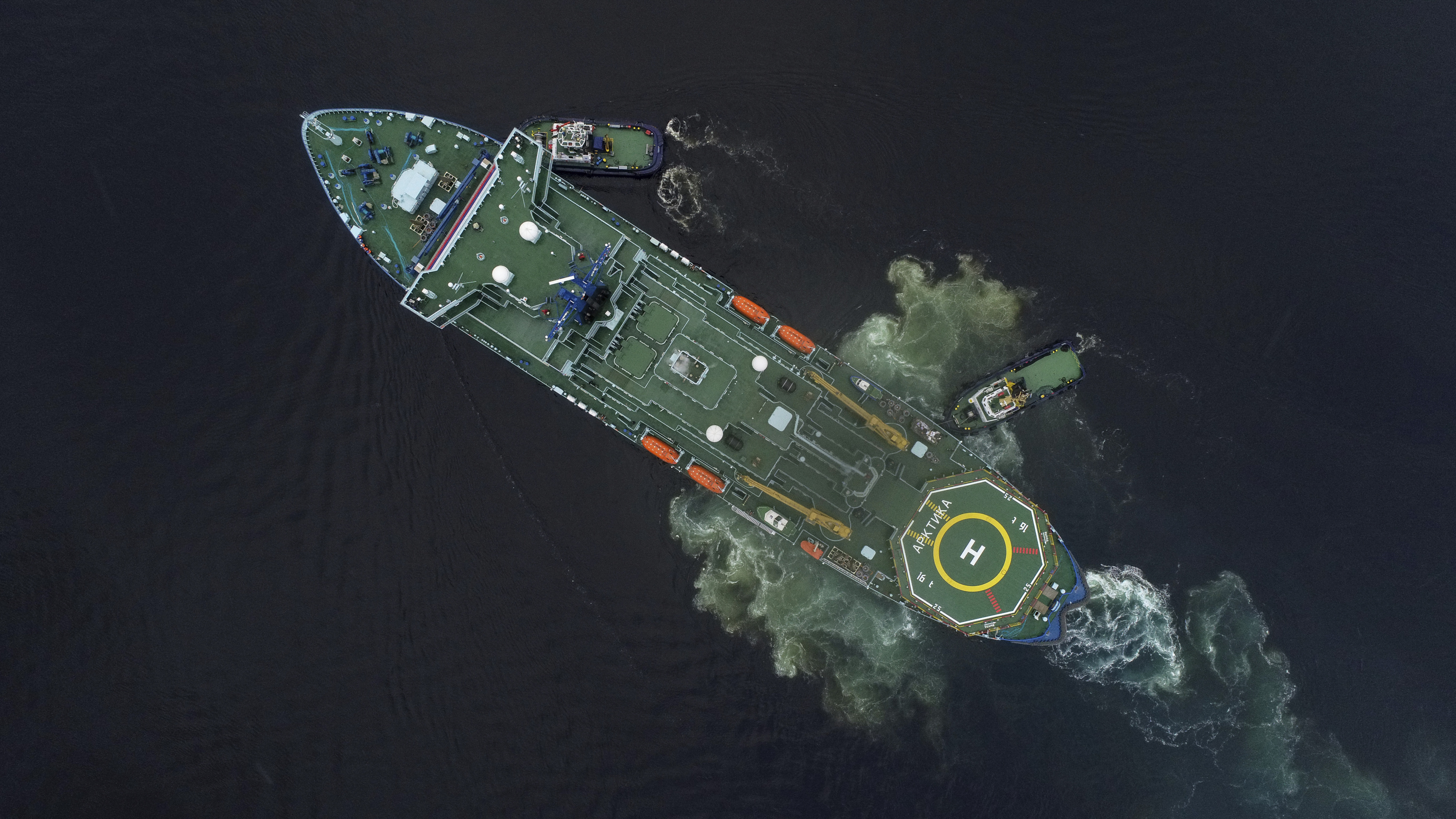 Aerial view of a large green ship in the ocean.