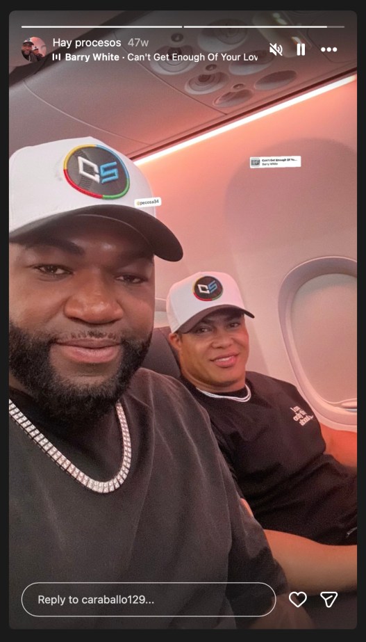 An Instagram Story screenshot of David Ortiz and another man smiling on an airplane wearing matching white baseball caps.