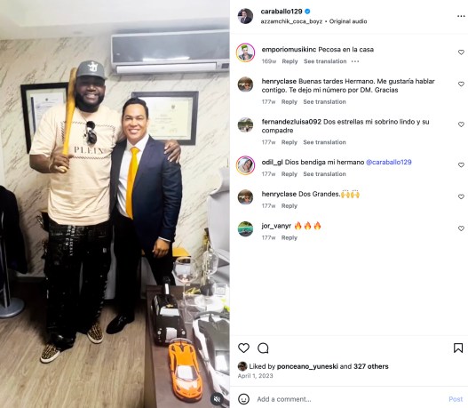 An Instagram post showing David Ortiz posing with a wooden bat alongside a man in a navy suit inside an office.