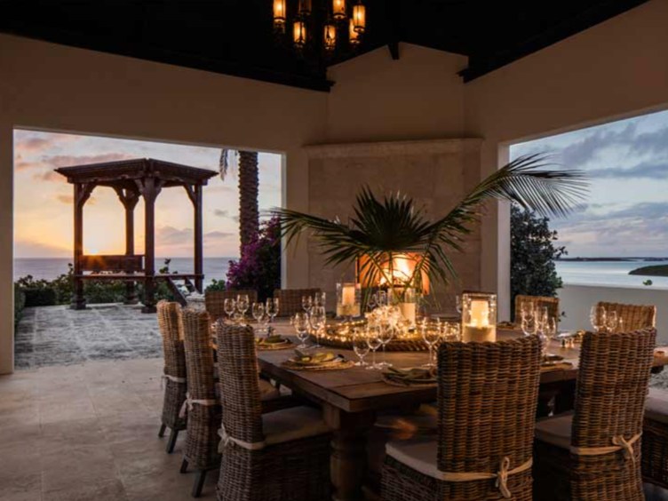 A set dining table with wicker chairs in a tropical setting.