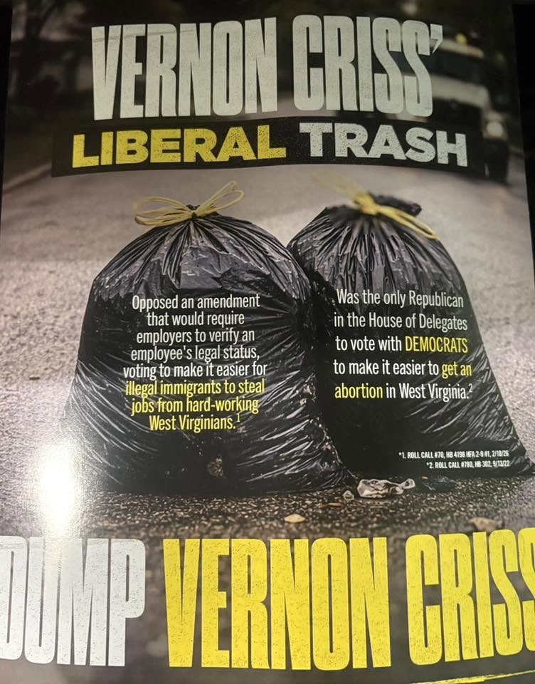 Two full garbage bags sit in the middle of an asphalt road. Large block lettering reads, “Vernon Criss’ liberal trash” and “Dump Vernon Criss.”